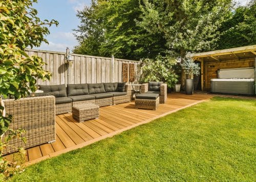 Neat paved patio with sitting area and small garden near wooden fence